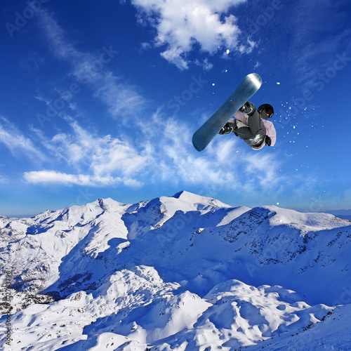 Skier Snowboarder jumping through air with sky in background