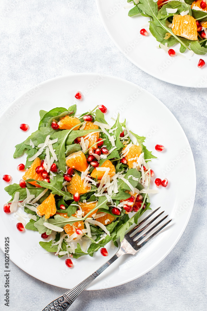 Fresh green organic salad with raw ingredients close up. Tasty salad with arugula, orange slices, pomegranate and cheese on white plate, top view. Healthy eating, dieting concept Fresh green organic salad with raw ingredients close up. Tasty salad with arugula, orange slices, pomegranate and cheese on white plate, top view. Healthy eating, dieting concept