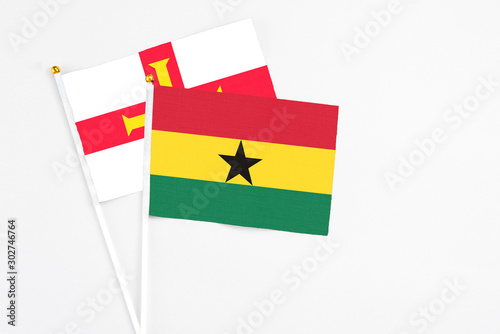 Ghana and Guernsey stick flags on white background. High quality fabric  miniature national flag. Peaceful global concept.White floor for copy space.