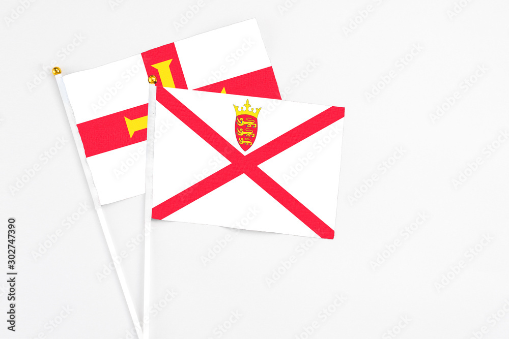Jersey and Guernsey stick flags on white background. High quality fabric, miniature national flag. Peaceful global concept.White floor for copy space. Jersey and Guernsey stick flags on white background. High quality fabric, miniature national flag. Peaceful global concept.White floor for copy space.