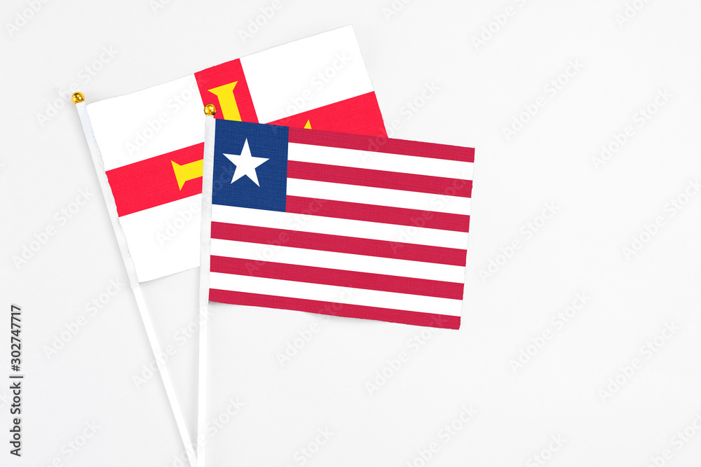 Liberia and Guernsey stick flags on white background. High quality fabric, miniature national flag. Peaceful global concept.White floor for copy space. Liberia and Guernsey stick flags on white background. High quality fabric, miniature national flag. Peaceful global concept.White floor for copy space.