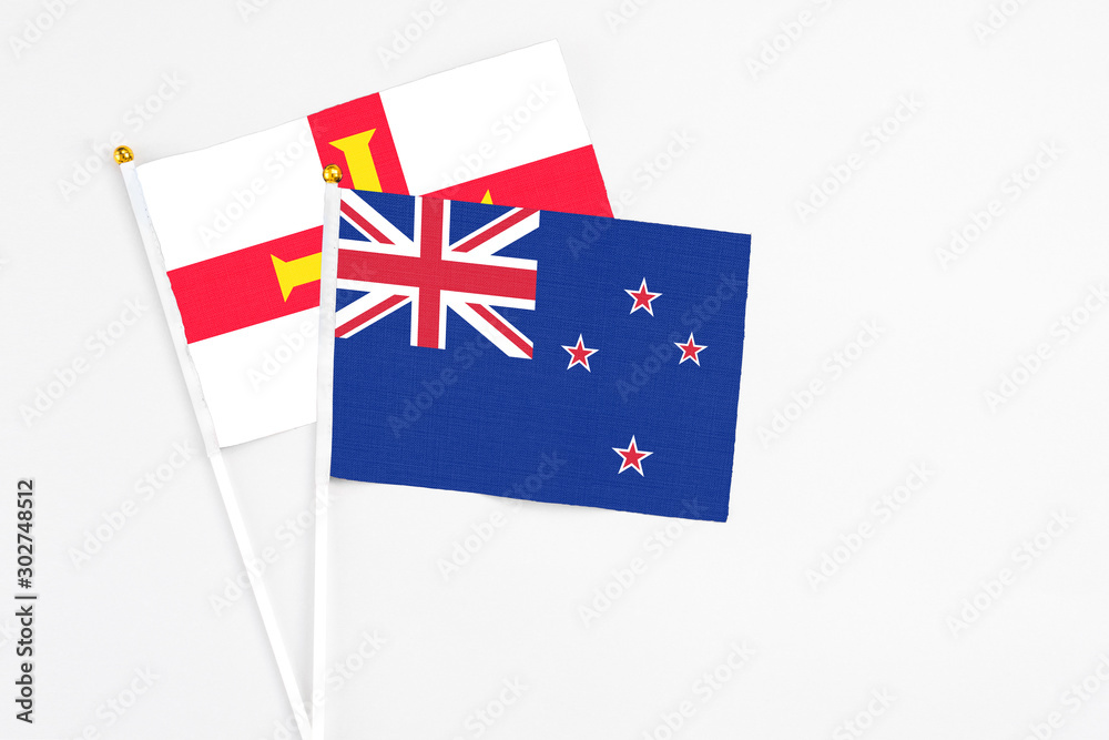 New Zealand and Guernsey stick flags on white background. High quality fabric, miniature national flag. Peaceful global concept.White floor for copy space. New Zealand and Guernsey stick flags on white background. High quality fabric, miniature national flag. Peaceful global concept.White floor for copy space.
