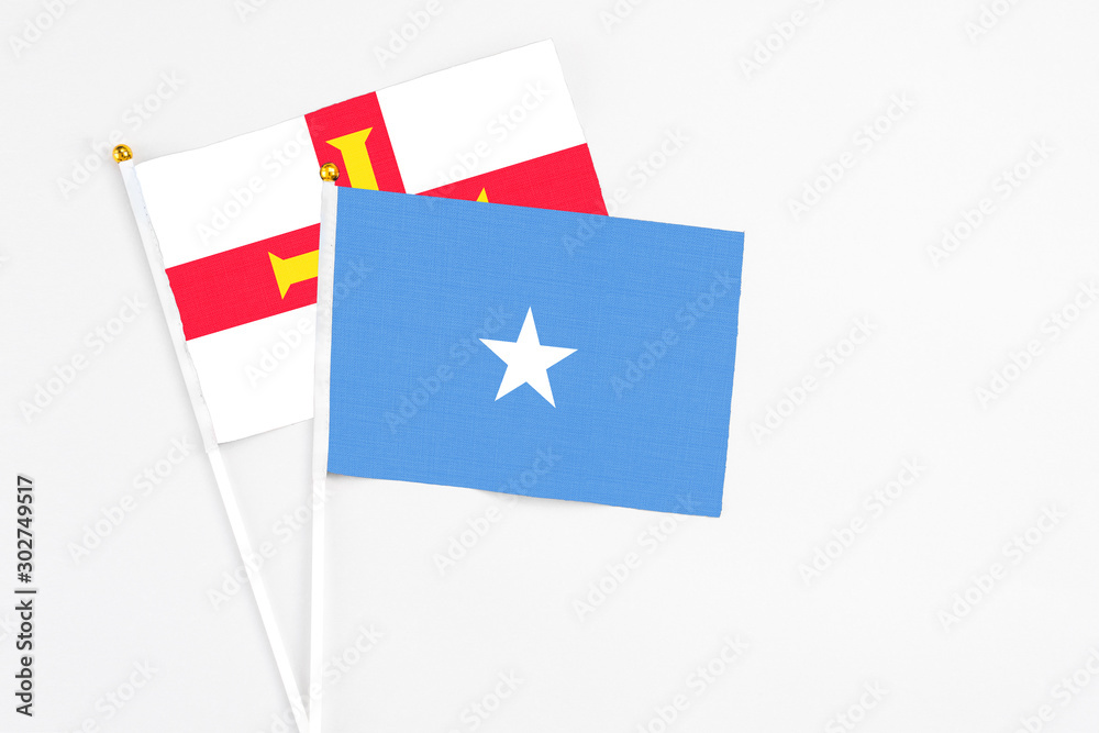 Somalia and Guernsey stick flags on white background. High quality fabric, miniature national flag. Peaceful global concept.White floor for copy space.