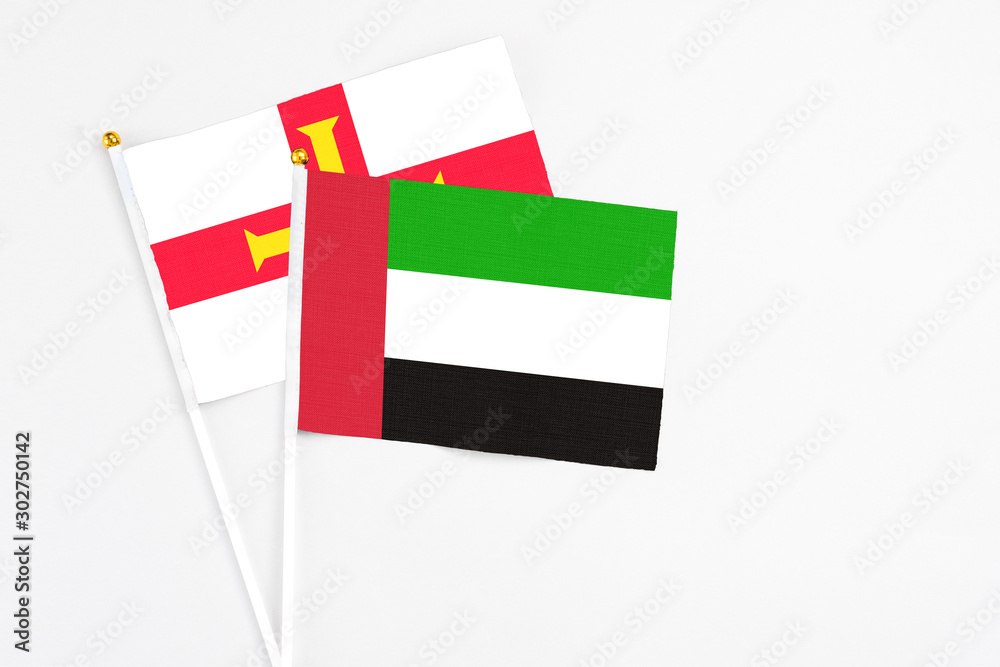 United Arab Emirates and Guernsey stick flags on white background. High quality fabric, miniature national flag. Peaceful global concept.White floor for copy space. United Arab Emirates and Guernsey stick flags on white background. High quality fabric, miniature national flag. Peaceful global concept.White floor for copy space.