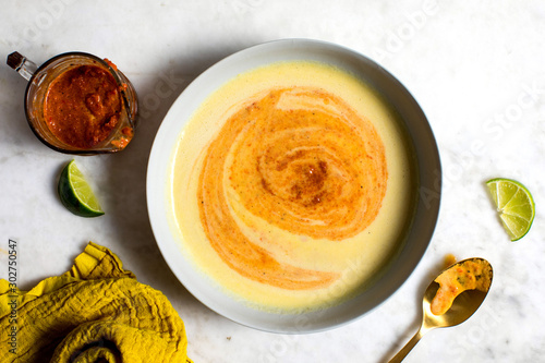 Overhead view of corn soup with red pepper swirl