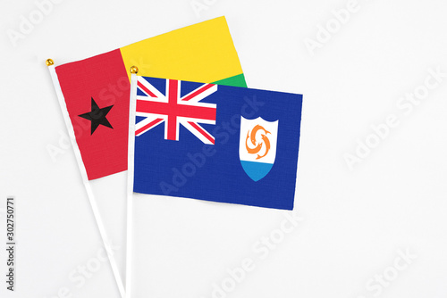 Anguilla and Guinea Bissau stick flags on white background. High quality fabric, miniature national flag. Peaceful global concept.White floor for copy space.