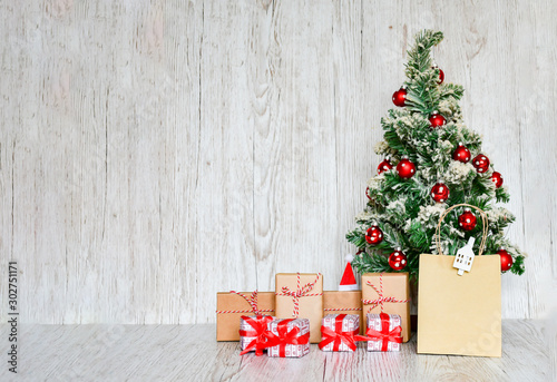 Selective focus Christmas tree with set of gift boxes tight with red ribbins, handmade objects on wood gray background. Christmas holiday concept. photo