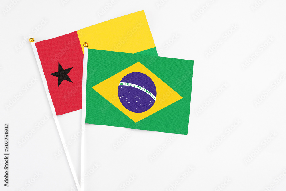 Brazil and Guinea Bissau stick flags on white background. High quality fabric, miniature national flag. Peaceful global concept.White floor for copy space.