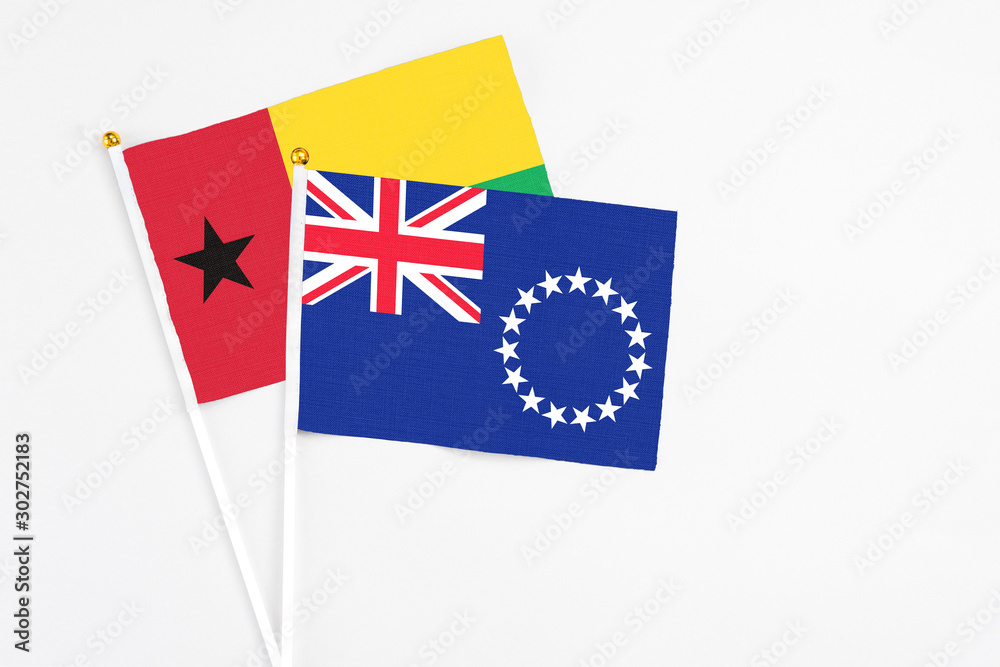 Cook Islands and Guinea Bissau stick flags on white background. High quality fabric, miniature national flag. Peaceful global concept.White floor for copy space. Cook Islands and Guinea Bissau stick flags on white background. High quality fabric, miniature national flag. Peaceful global concept.White floor for copy space.