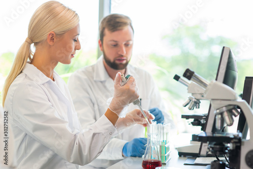 Scientist working in lab. Doctors making medical research. Biotechnology  chemistry  science  experiments and healthcare concept. Day light and window background.
