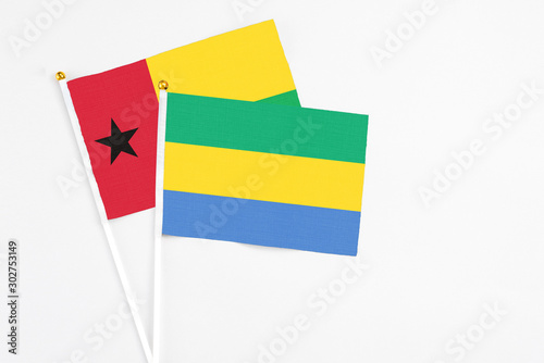 Gabon and Guinea Bissau stick flags on white background. High quality fabric, miniature national flag. Peaceful global concept.White floor for copy space. photo