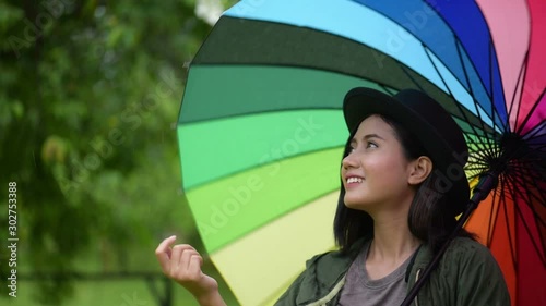 asian beautiful woman play raindrop from colorful umbrella .She turn and spin the many color umbrella  With feeling fun cheerful gesture Refreshing and jovial in the rain. Enjoy life in nature concept