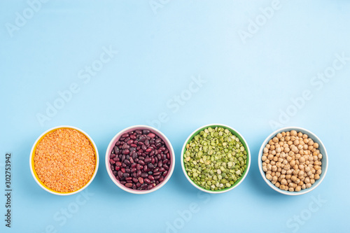 Dried beans, lentils, green horn and chickpeas in round plates on a blue background
