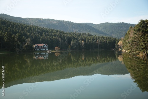 Wooden Lake house inside forest in Bolu Golcuk National Park, Turkey with reflection on the lake on cloudy sky.