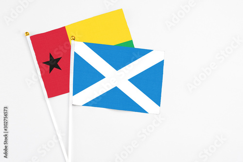 Scotland and Guinea Bissau stick flags on white background. High quality fabric, miniature national flag. Peaceful global concept.White floor for copy space.