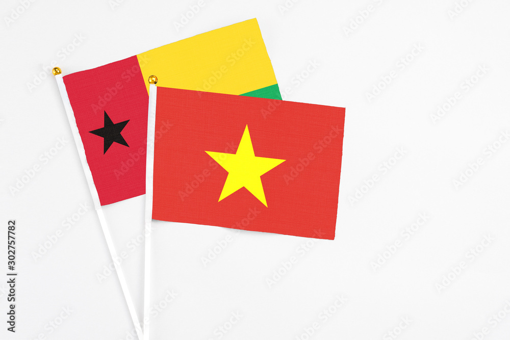 Vietnam and Guinea Bissau stick flags on white background. High quality fabric, miniature national flag. Peaceful global concept.White floor for copy space.