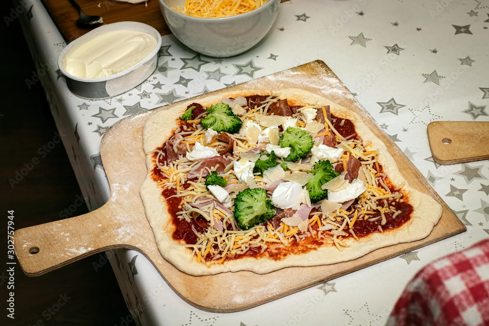 VOrbereitete Pizza vor dem Backen auf Holzschieber mit Zutaten – Stock-Foto  | Adobe Stock