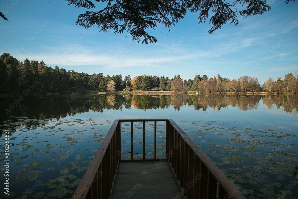 Naklejka premium Wooden pier at autumn lake, fall colors