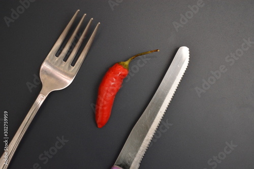 peperoncino rosso piccante ingrediente per cucinare su tavolo con forchetta e coltello di metallo