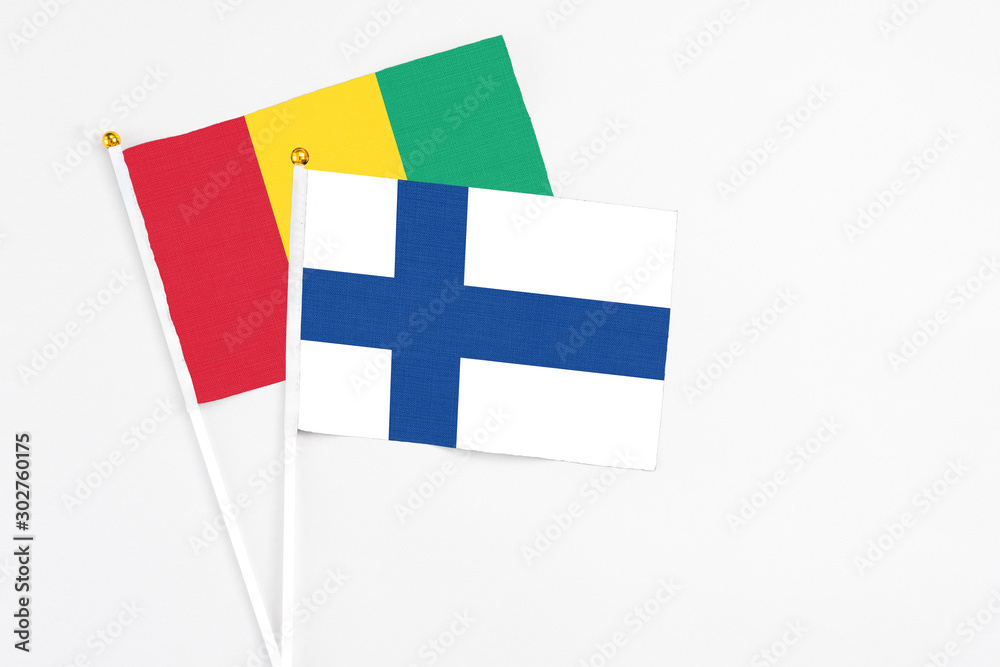 Finland and Guinea stick flags on white background. High quality fabric, miniature national flag. Peaceful global concept.White floor for copy space. Finland and Guinea stick flags on white background. High quality fabric, miniature national flag. Peaceful global concept.White floor for copy space.