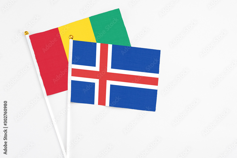 Iceland and Guinea stick flags on white background. High quality fabric, miniature national flag. Peaceful global concept.White floor for copy space.