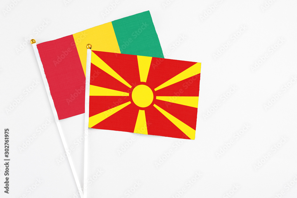 Macedonia and Guinea stick flags on white background. High quality fabric, miniature national flag. Peaceful global concept.White floor for copy space.
