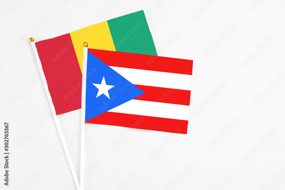 Puerto Rico and Guinea stick flags on white background. High quality fabric, miniature national flag. Peaceful global concept.White floor for copy space. Puerto Rico and Guinea stick flags on white background. High quality fabric, miniature national flag. Peaceful global concept.White floor for copy space.