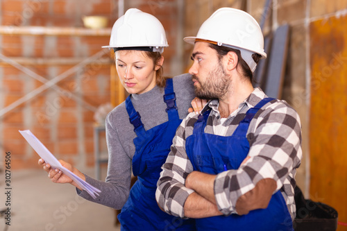 Workers man and woman discuss construction plan