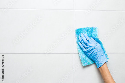 cleaning the toilet room, a hand in a blue glove washes a tile.