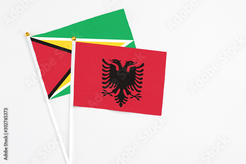 Albania and Guyana stick flags on white background. High quality fabric, miniature national flag. Peaceful global concept.White floor for copy space.