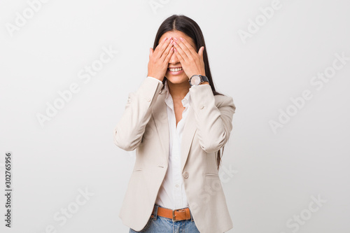 Young business arab woman isolated against a white background covers eyes with hands, smiles broadly waiting for a surprise.