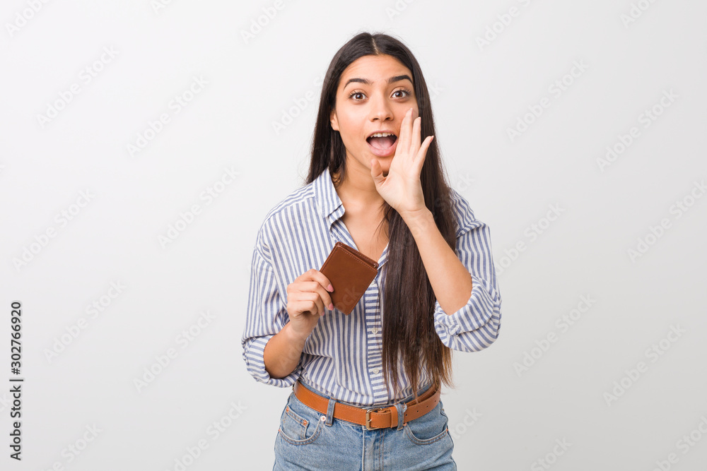 Young arab woman holding a wallet shouting excited to front. Young arab woman holding a wallet shouting excited to front.