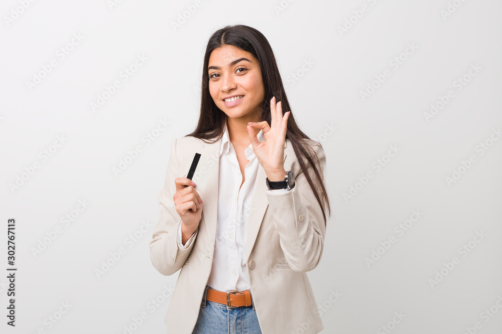 Young arab woman holding a credit card cheerful and confident showing ok gesture. Young arab woman holding a credit card cheerful and confident showing ok gesture.