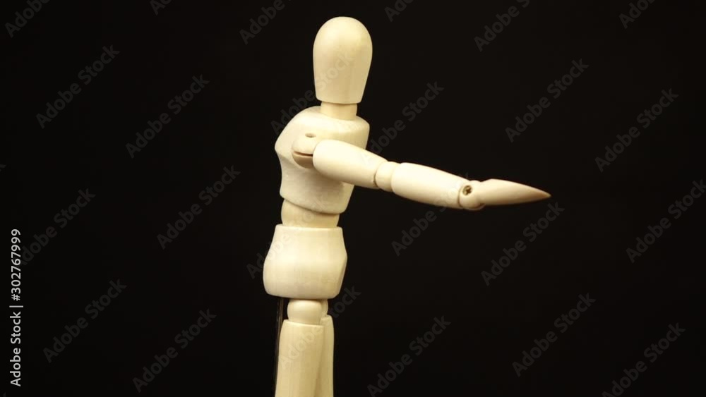 the wooden doll pulls its arm forward and rotates 360 degrees on a black background the wooden doll pulls its arm forward and rotates 360 degrees on a black background