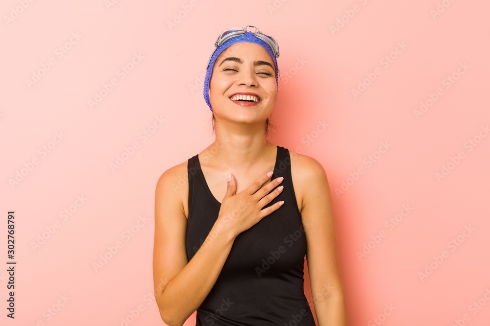 Young arab swimmer woman isolated laughs out loudly keeping hand on chest. Young arab swimmer woman isolated laughs out loudly keeping hand on chest.