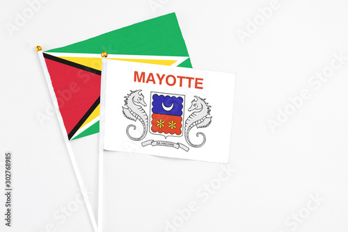 Mayotte and Guyana stick flags on white background. High quality fabric, miniature national flag. Peaceful global concept.White floor for copy space.