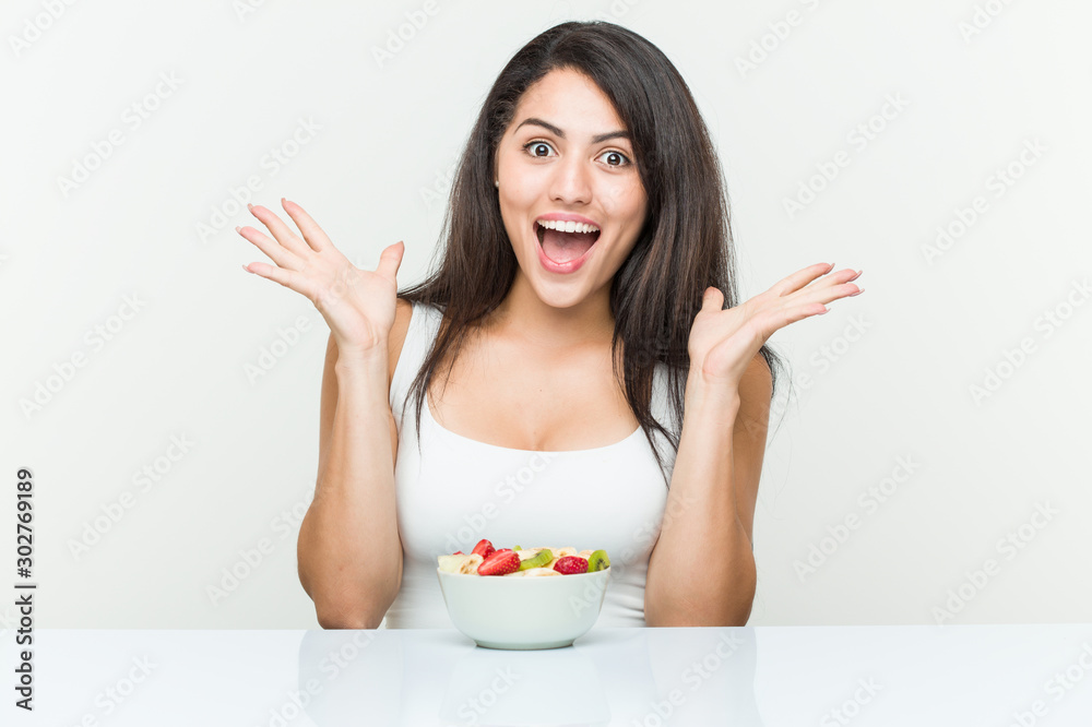 Young hispanic woman eating a fruit bowl celebrating a victory or success Young hispanic woman eating a fruit bowl celebrating a victory or success