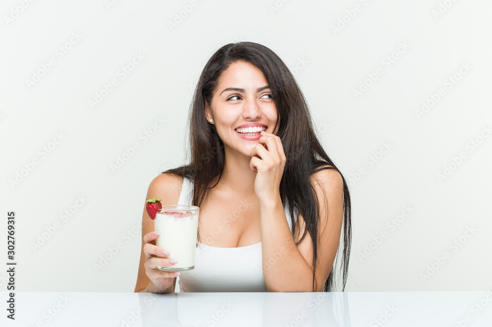 Young hispanic woman holding a smoothie young hispanic woman holding an avocado toast relaxed thinking about something looking at a copy space.< mixto > Young hispanic woman holding a smoothie young hispanic woman holding an avocado toast relaxed thinking about something looking at a copy space.< mixto >
