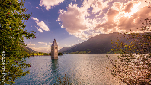 The sun is setting at the abandoned bell tower in Lake Reschen or Reschensee (Alto Adige or South Tyrol, Italy) on a early September evening. It is located near the border between Austria and Italy.