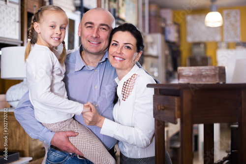 Smiling couple with their daughter in furniture showroom