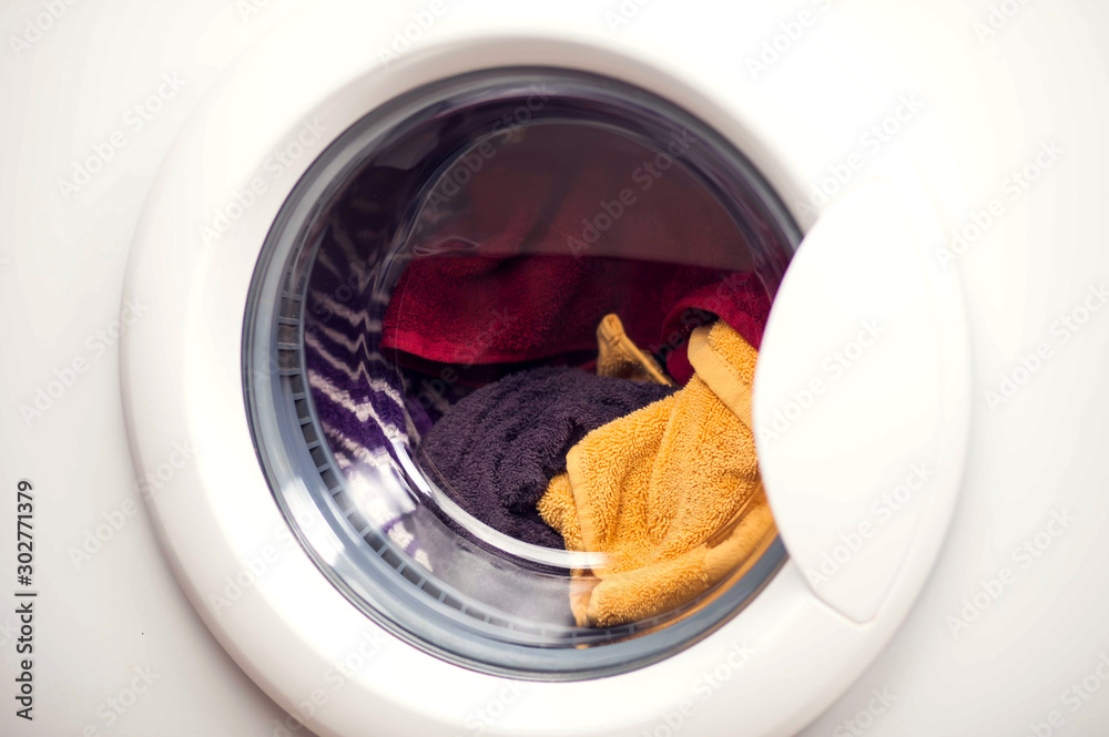 White washing machine door full of clothes, close up. Laundry concept White washing machine door full of clothes, close up. Laundry concept