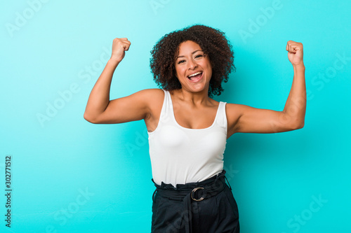 Young african american woman showing strength gesture with arms, symbol of feminine power