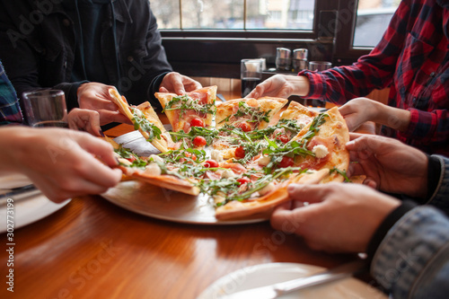 group of students friends eat Italian pizza, hands take slices of pizza in a restaurant photo