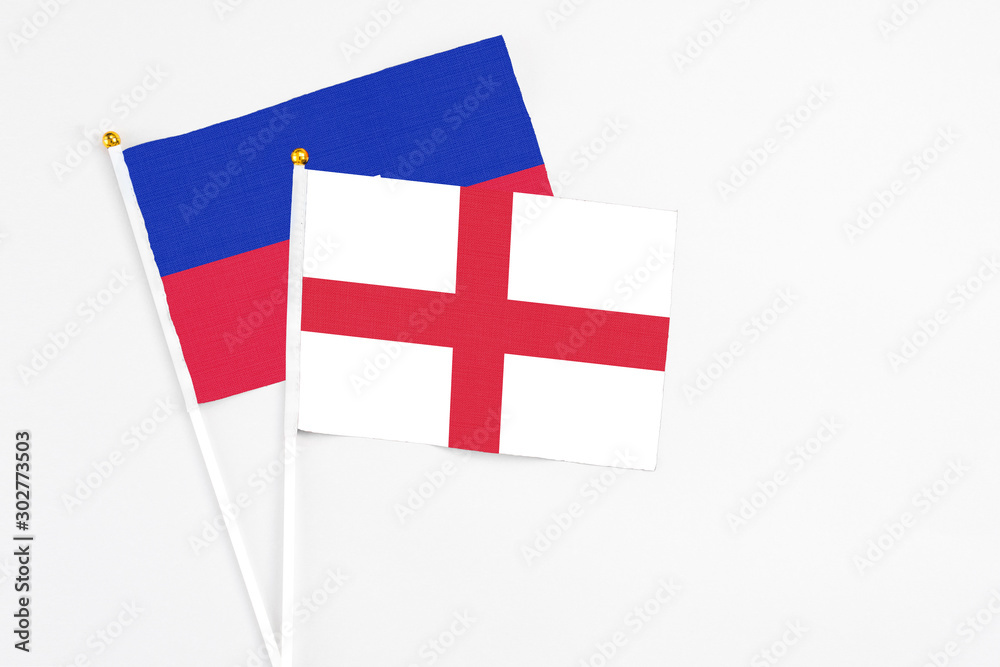England and Haiti stick flags on white background. High quality fabric, miniature national flag. Peaceful global concept.White floor for copy space.