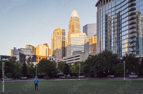 Person walking on a park with modern buildings in the background © GuRezende