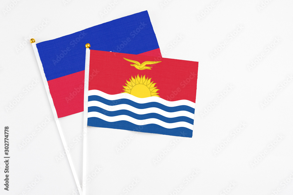 Naklejka premium Kiribati and Haiti stick flags on white background. High quality fabric, miniature national flag. Peaceful global concept.White floor for copy space.