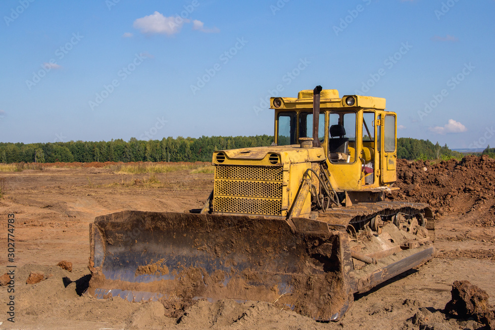 An old industrial bulldozer is parked at a construction site. An old industrial bulldozer is parked at a construction site.