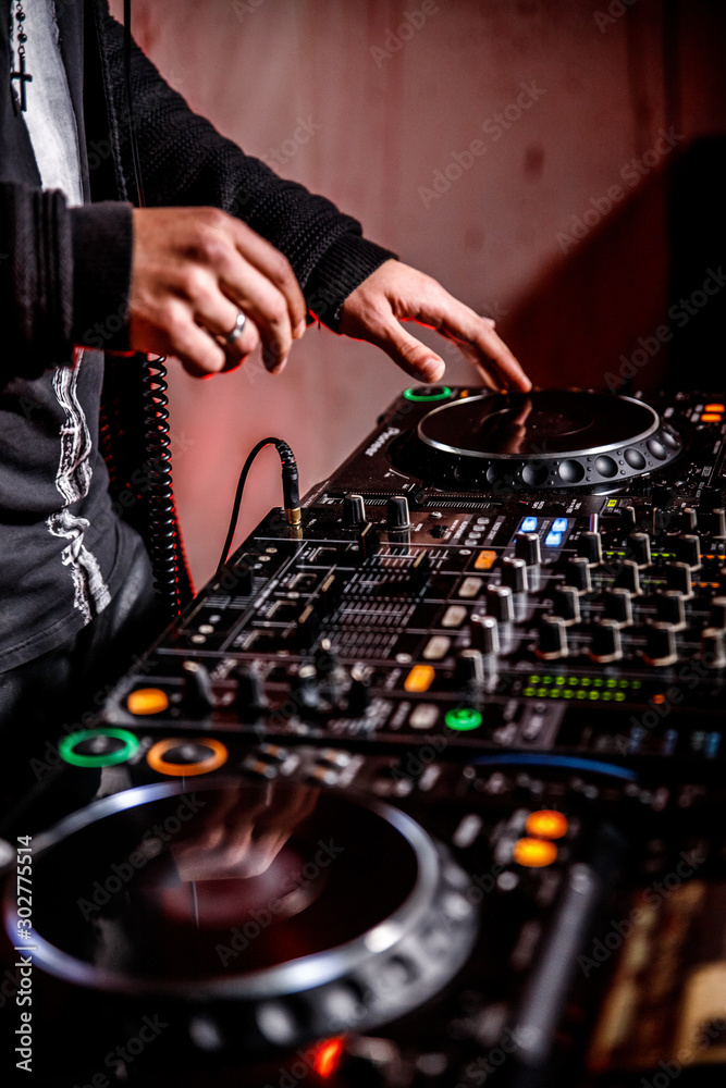 DJ plays live set and mixing music on turntable console at stage in the  night club.