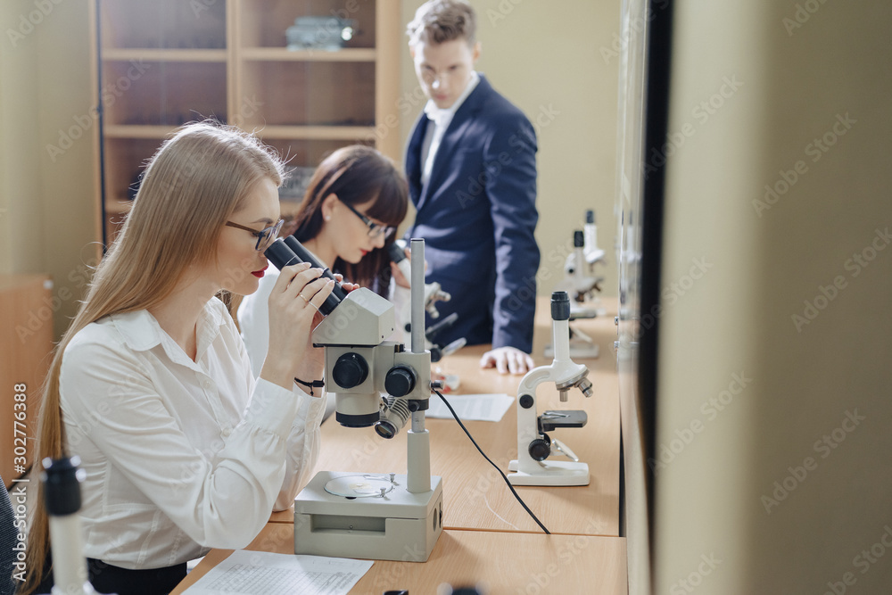 two girls and a boy work with microscopes two girls and a boy work with microscopes