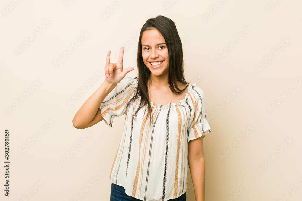 Young hispanic woman showing a horns gesture as a revolution concept. Young hispanic woman showing a horns gesture as a revolution concept.